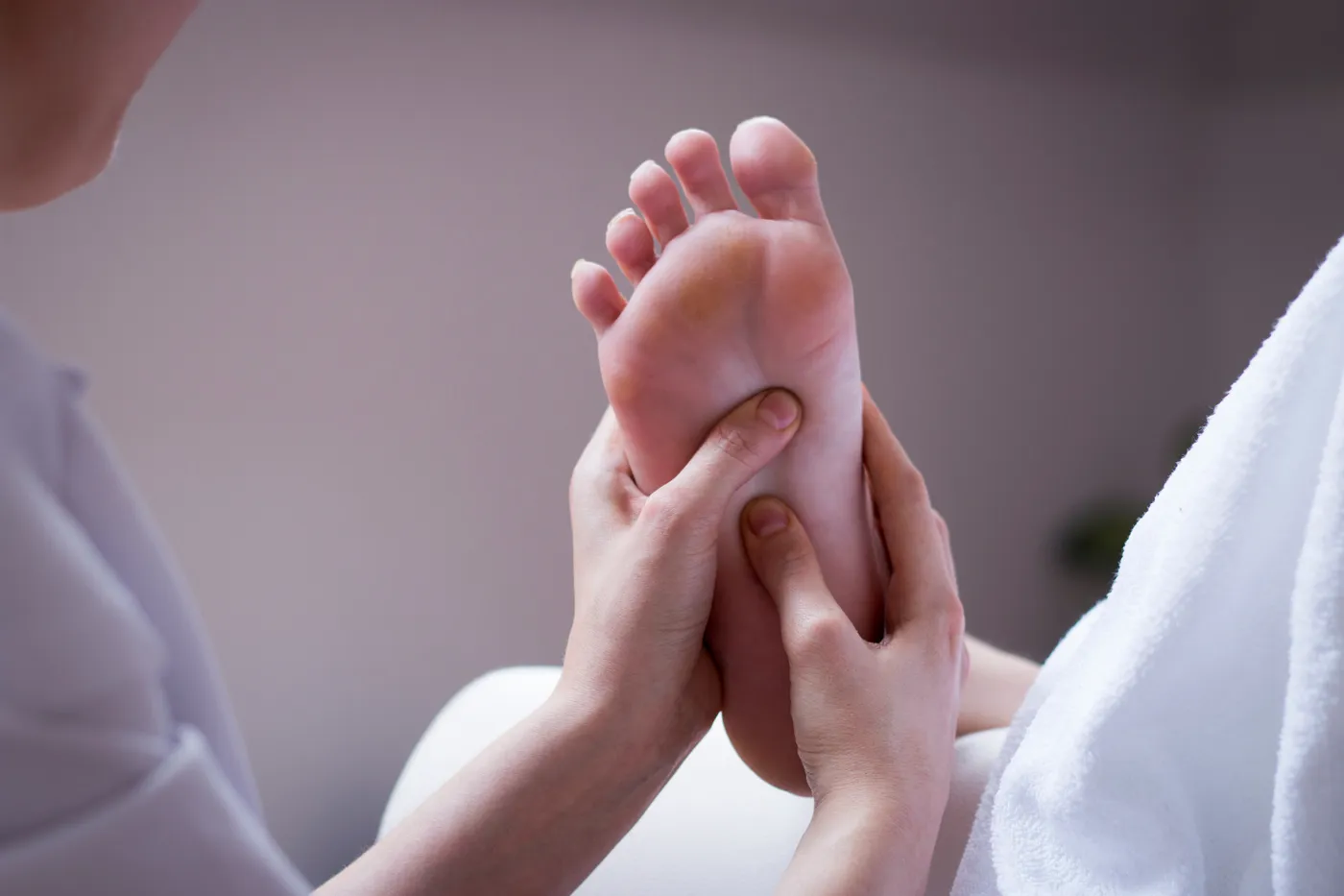 Refleksna masaža stopal — terapevt s palcem pritiska na stopalo med terapijo